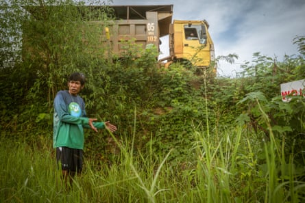 A man stands in a rice field as a truck drives past behind him