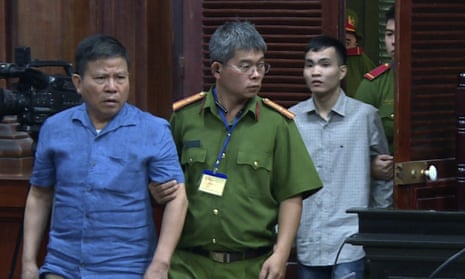 Sydney man Chau Van Kham, left, is escorted into a court room in Vietnam