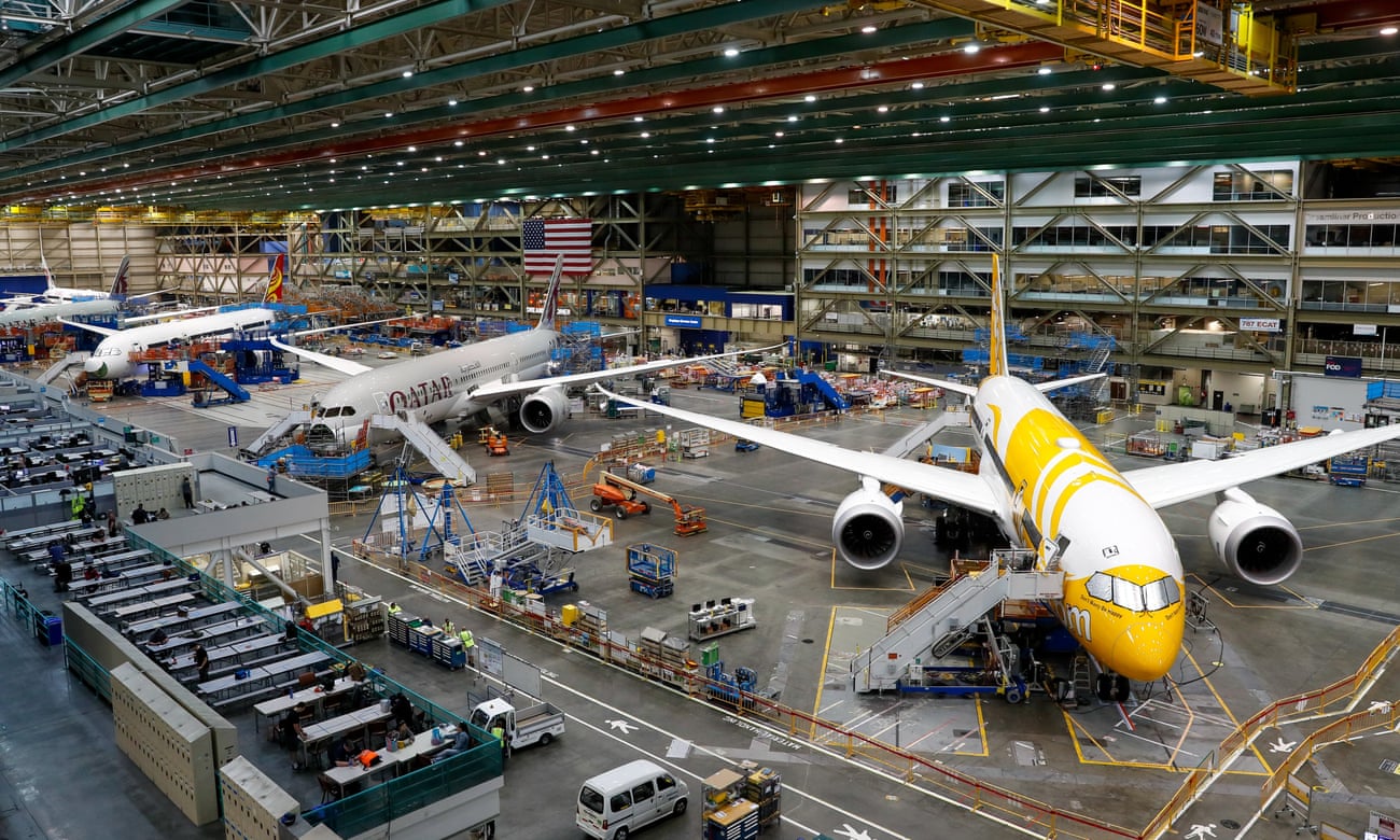Four planes with liveries of different airlines parked inside the giant factory, dwarfing service vehicles and workers