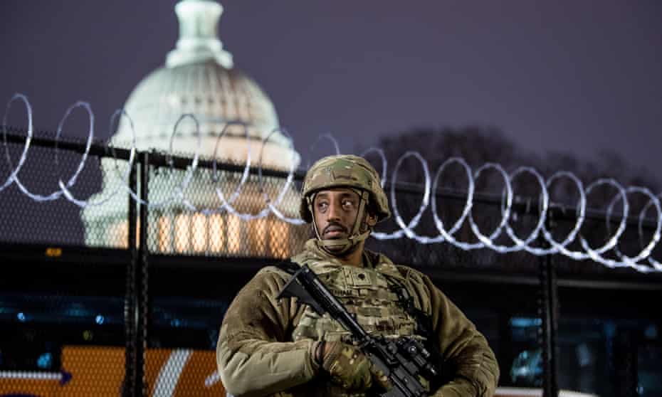 A member of the Virginia national guard stands outside razor wire fencing surrounding the US Capitol.