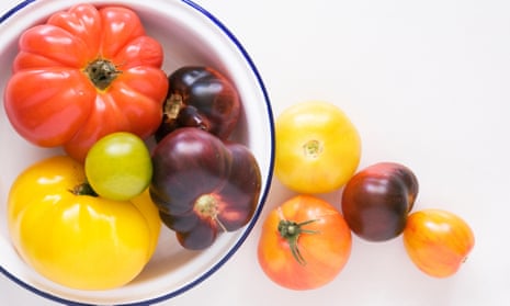 Brightly coloured heritage tomatoes in an enamel dish.