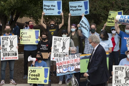 people hold up signs protesting a pipeline