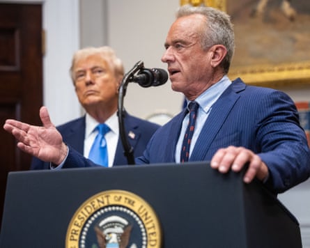 A besuited man, Robert F Kennedy Jr, speaks at a lecturn, with trump looking on