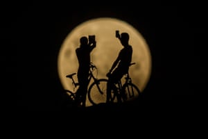 Cyclists take photos of the super moon in Lancelin, Australia