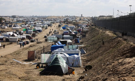 Displaced Palestinians shelter near the border fence with Egypt in Rafah