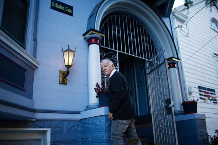 Bob Buckter stands in front of his house, painted blue according to his designed color scheme.