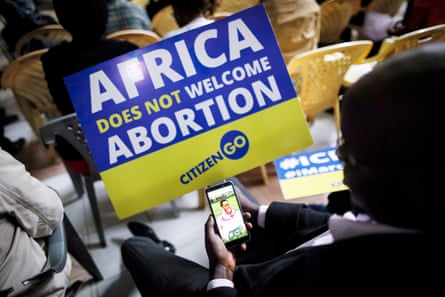 An anti-abortion activist holds a placard saying ‘Africa does not welcome abortion’ as he looks at a photo of his baby daughter on a mobile phone during a rally organised by CitizenGo