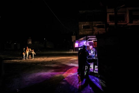 Two men talk under the light of a roadside stall as a