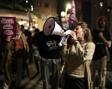 A woman shouts into a megaphone in the middle of a crowd of protesters.