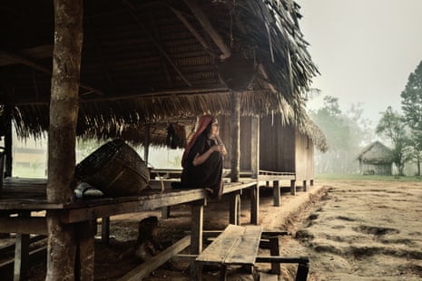 Woman sits in open-sided hut with thatched roof