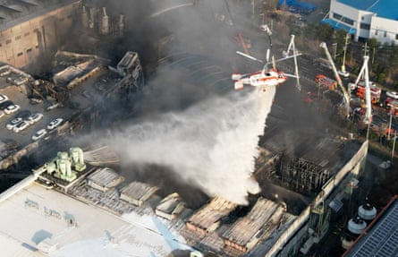 A helicopter drops water on to the smoking building