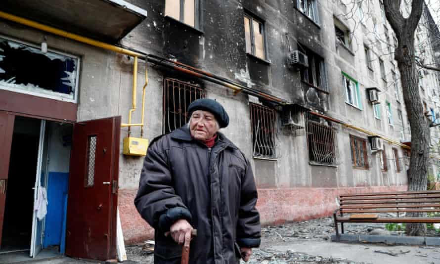 Maria Miroshnichenko, 84, a former social services worker, stands outside a heavily damaged residential building in Mariupol.