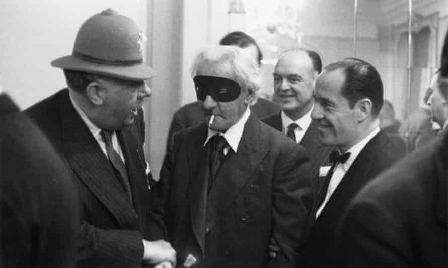 Hannen Swaffer, with mask and cigarette, at a party in December 1955.