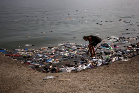 A man bends down to pick through various pieces of washed-up objects