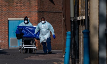 BAME hospital workers in full PPE transporting a blue trolley