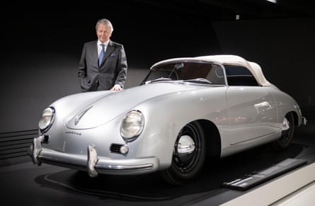 Wolfgang Porsche stands behind a luxury Porsche sports car with a hand on the bonnet