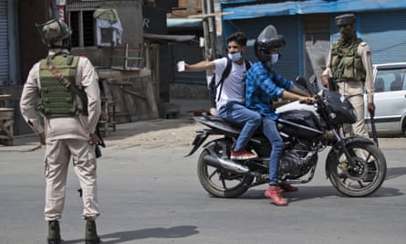 A Kashmiri man shows his ID card to soldiers during a curfew in Srinagar.