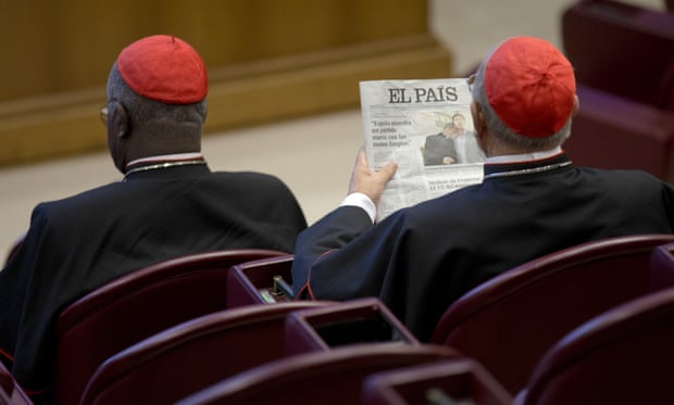 Spanish cardinal Ricardo Blázquez Pérez reads a newspaper showing a picture of Krzysztof Charamsa and his partner Eduard before the start of the morning session of the synod of bishops on family issues, at the Vatican.