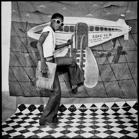A young man pretends to board a plane painted onto a backdrop. Autoportrait au Miroir by Sory Sanlé (1966)