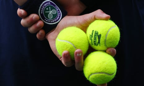 Close-up of a ball kid at Wimbledon holding three tennis balls in one hand.