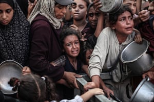 Children in tears hold out bowls and saucepans for food