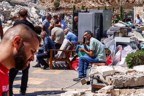 Palestinian men sit with furniture that was removed before the demolition of a Palestinian building by Israeli forces.