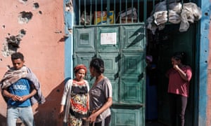 People stand outside a shop in Mekelle that was damaged in shelling when federal troops retook the town in November