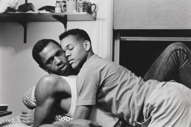 black and achromatic image of 2 men laying successful bed, leaning against each other