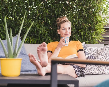 Relaxed woman sitting on couch on terrace at home drinking coffee.