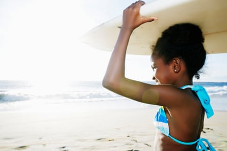 Girl carrying surfboard on beach
