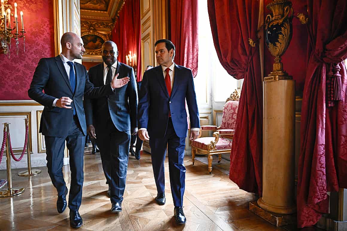 Three men walk together in a room.