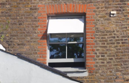 A window in a brick house with a shade over the top part