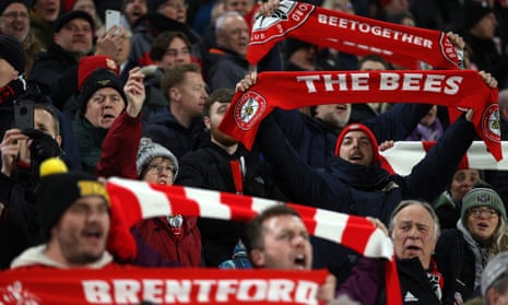 Brentford fans hold up their scarves as they sing ahead of kick-off during the Premier League match between Brentford and Fulham at Gtech Community Stadium.