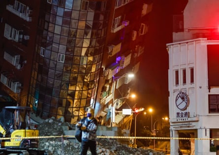 A man stands near a partially collapsed residential building in Hualien.