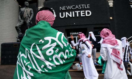 A fan of Newcastle United wearing traditional Saudi head dress and draped in a Saudi Arabia flag