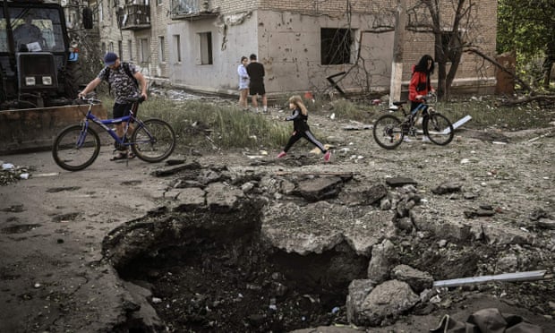 A young girl walks by a crater in front of a damaged apartment building after a strike in the city of Slovyansk in Donbas.