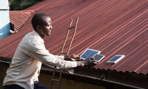 Placing solar panels on roof of house to charge, Longisa, Bomet district, Kenya