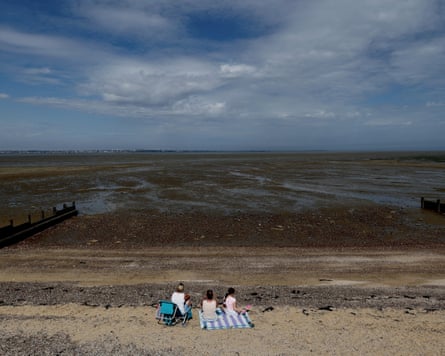 People sit on a beach at Allhallows on the Thames estuary as a yellow heat-health alert remains in force.