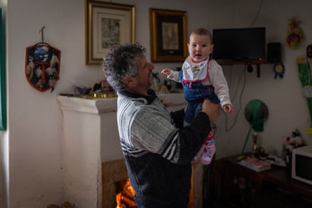 Paolo holding baby Lara at home by the fireplace.