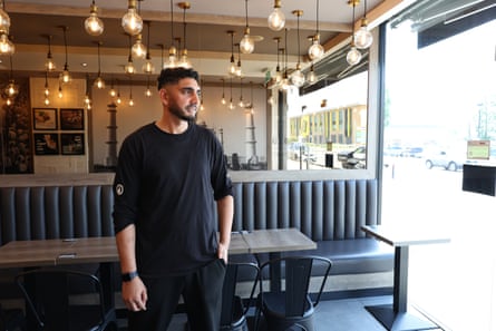 A man dressed in black stands in a cafe