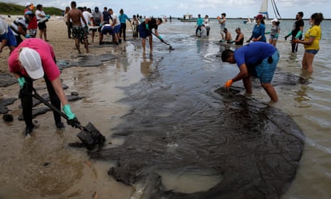 Environmental volunteers work to remove oil waste from Suape Beach, in Cabo de Agostinho, state of Pernambuco, Brazil.