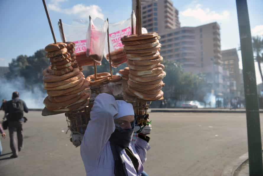 An Egyptian street vender sells bread as police fire teargas during clashes with protesters near Cairo’s Tahrir Square in 2013