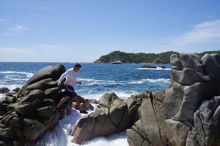 A man climbing over rocks by the sea