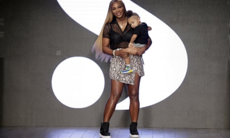 Serena Williams holding her daughter Alexis on stage with part of her S for Serena logo behind them