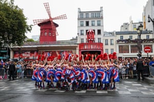 Dancers perform the cancan in front of the Moulin Rouge (red windmill) in Paris