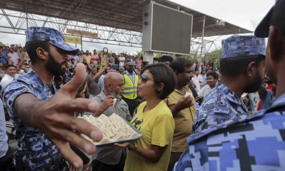 Eva Abdullah, of the Maldivian Democratic party, offers sandwiches to police personnel as they try to stop the party from holding political rallies on Friday.
