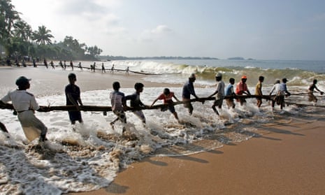 Sri Lankan fishermen pull their fishing net in on the beach in Baruwala