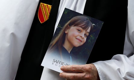 A member of the clergy holds a picture of Saffie-Rose Roussos