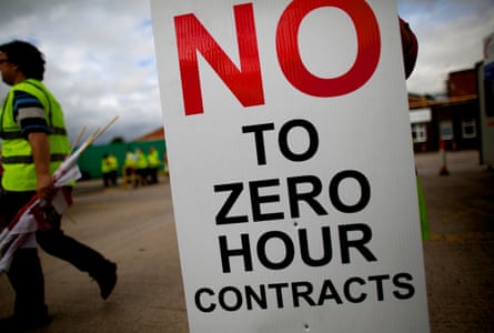 An individual in a hi-vis jacket walking past a sign saying 'No to zero hour contracts'