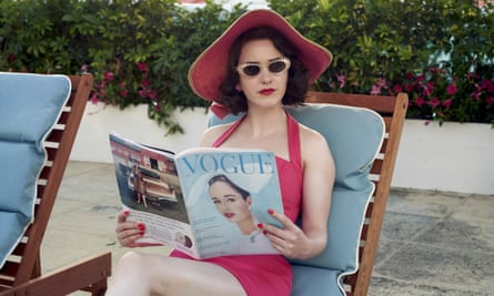 Rachel Brosnahan as Mrs Maisel, on a sunlounger in a one-piece, shades and a hat, and holding a copy of Vogue, in a scene from The Marvelous Mrs. Maisel